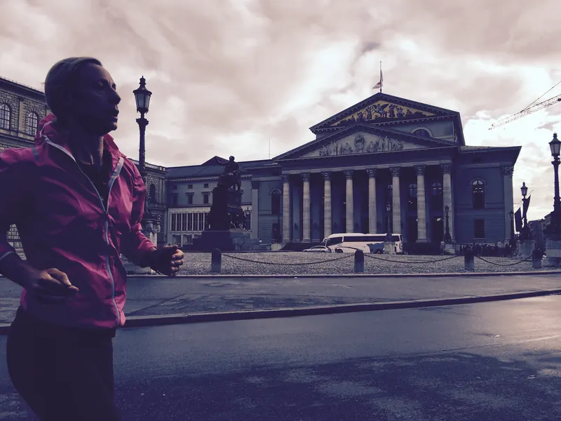 A woman in a pink jacket running past the Bavarian State Opera in Munich.